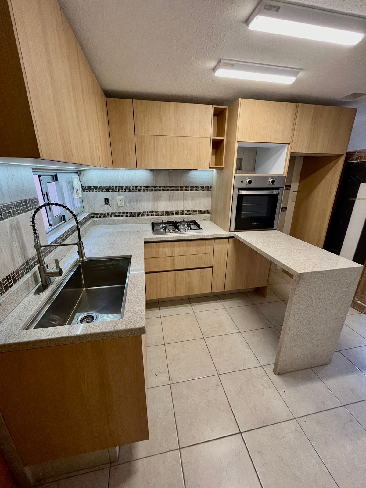 Cocina residencial en roble claro con cubierta de cuarzo