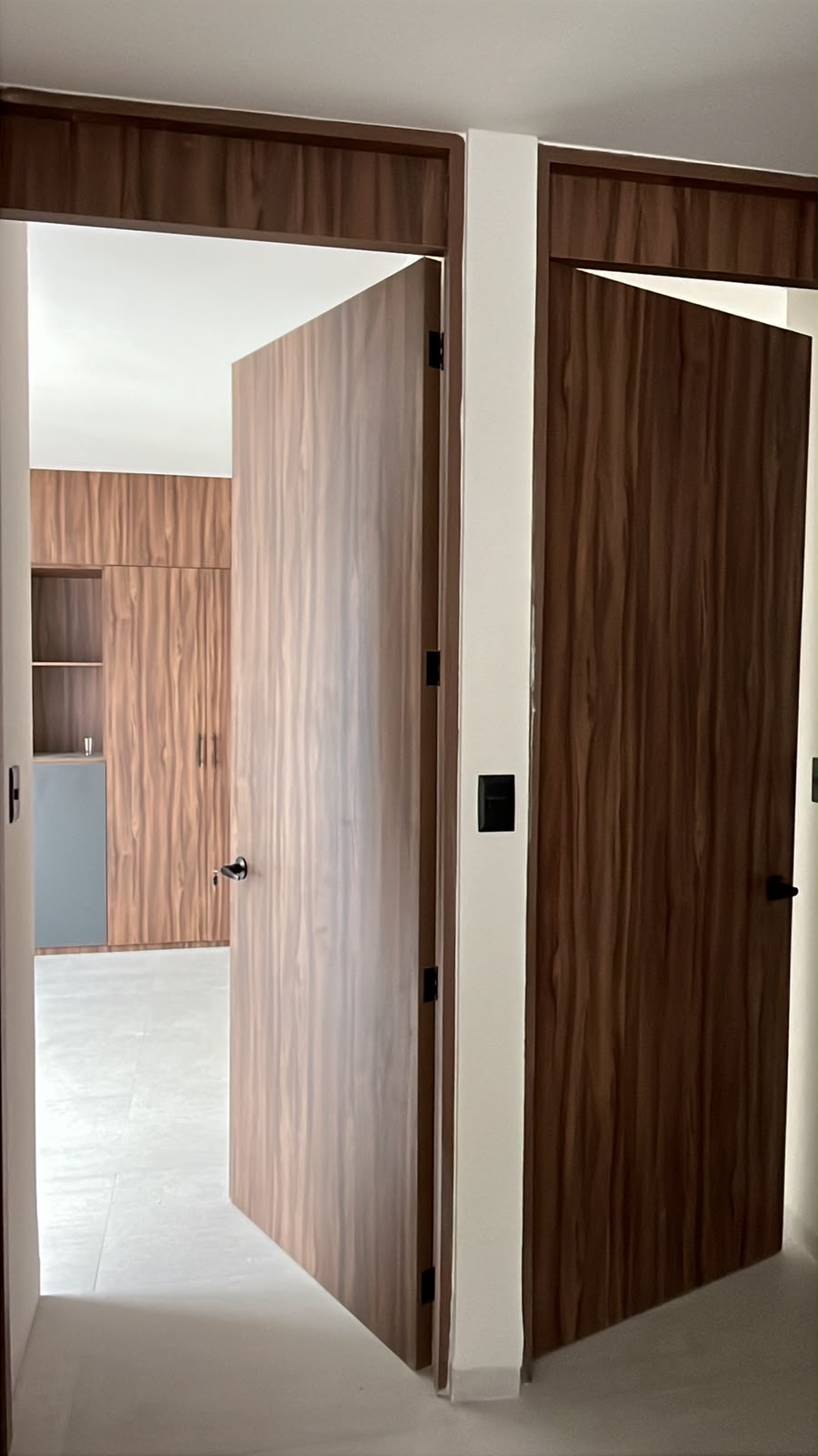 Puertas pivote de nogal a piso con clósets a juego en pasillo